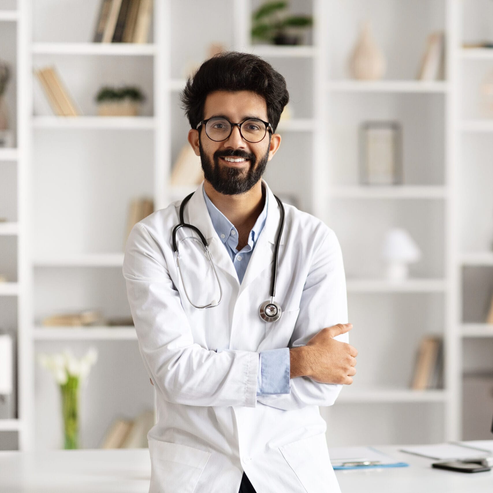 Indian Doctor Poses Beside Computer in Clinic Setting siti web per medici