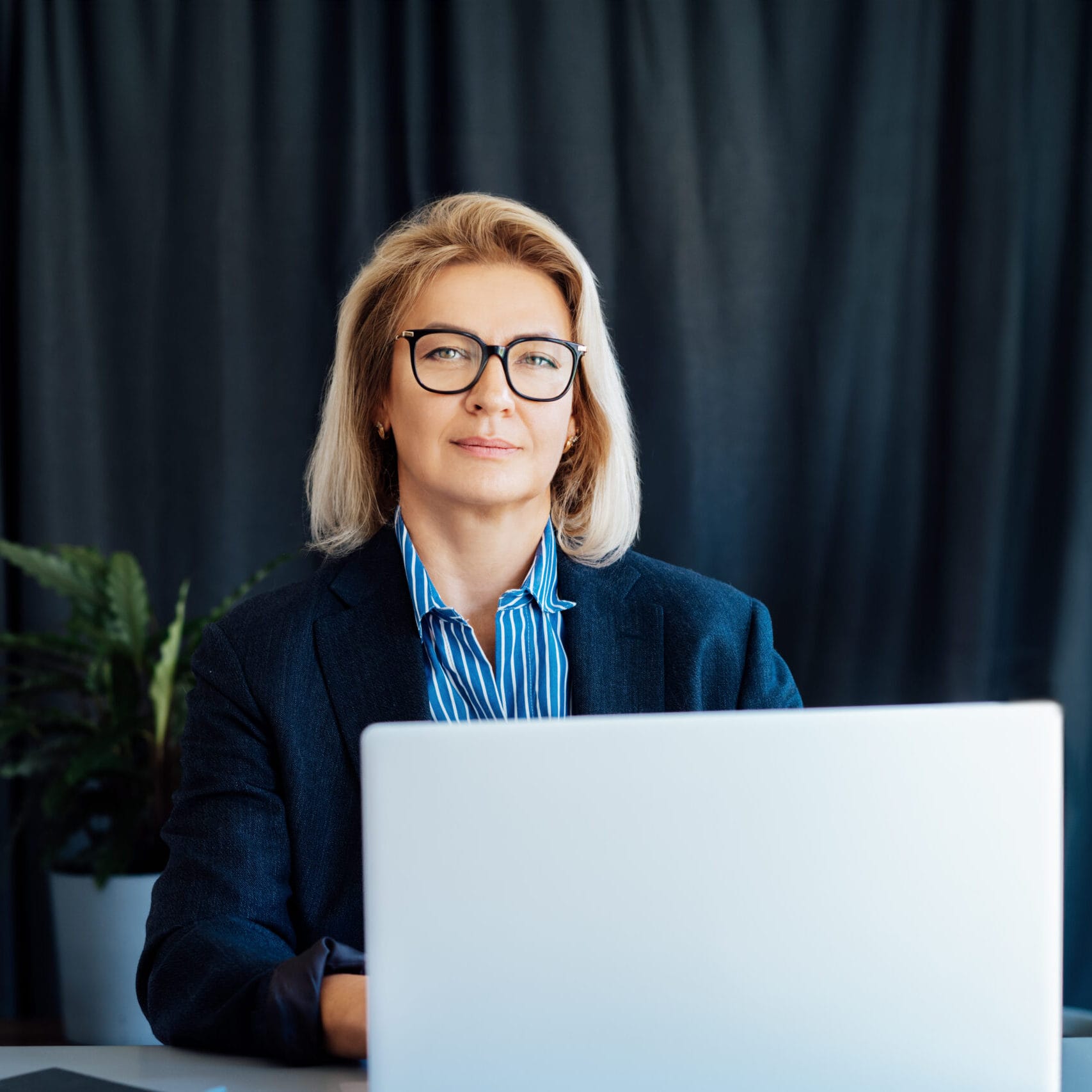 Portrait of smiling 50's stylish, confident mature businesswoman, middle aged company ceo director, experienced senior female professional, business coach working on laptop in office. Female leader. siti per professionisti